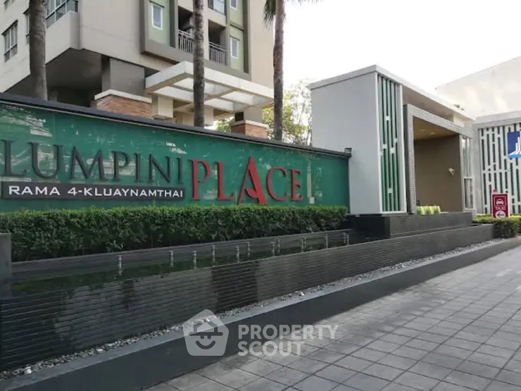 Modern condominium entrance with stylish signage and lush greenery.