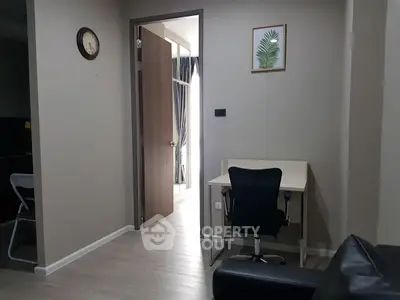 Modern apartment interior with study area and open doorway, showcasing sleek design and neutral tones.
