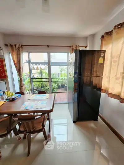 Bright kitchen with dining area and balcony access, featuring modern appliances and garden view.