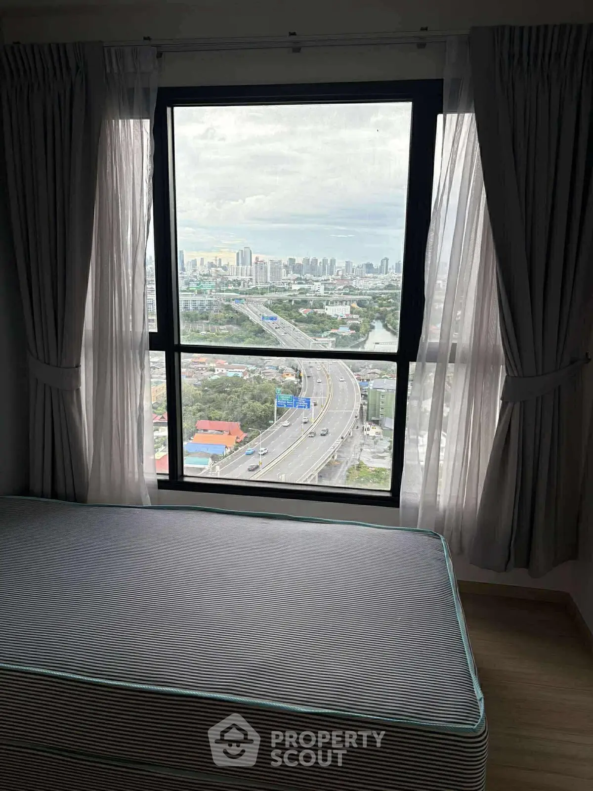High-rise bedroom with large window offering stunning cityscape view.