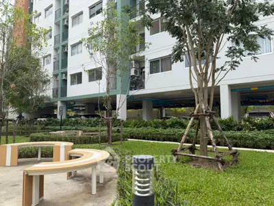 Modern apartment building exterior with landscaped garden and seating area.