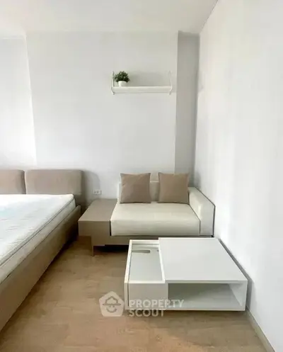 Modern minimalist bedroom with cozy seating area and neutral tones.