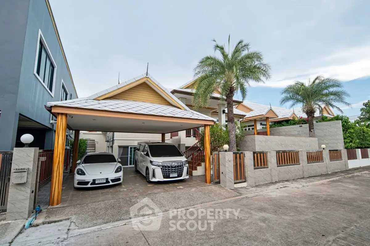 Luxurious modern house with spacious driveway and palm trees, featuring two luxury cars parked under a stylish carport.