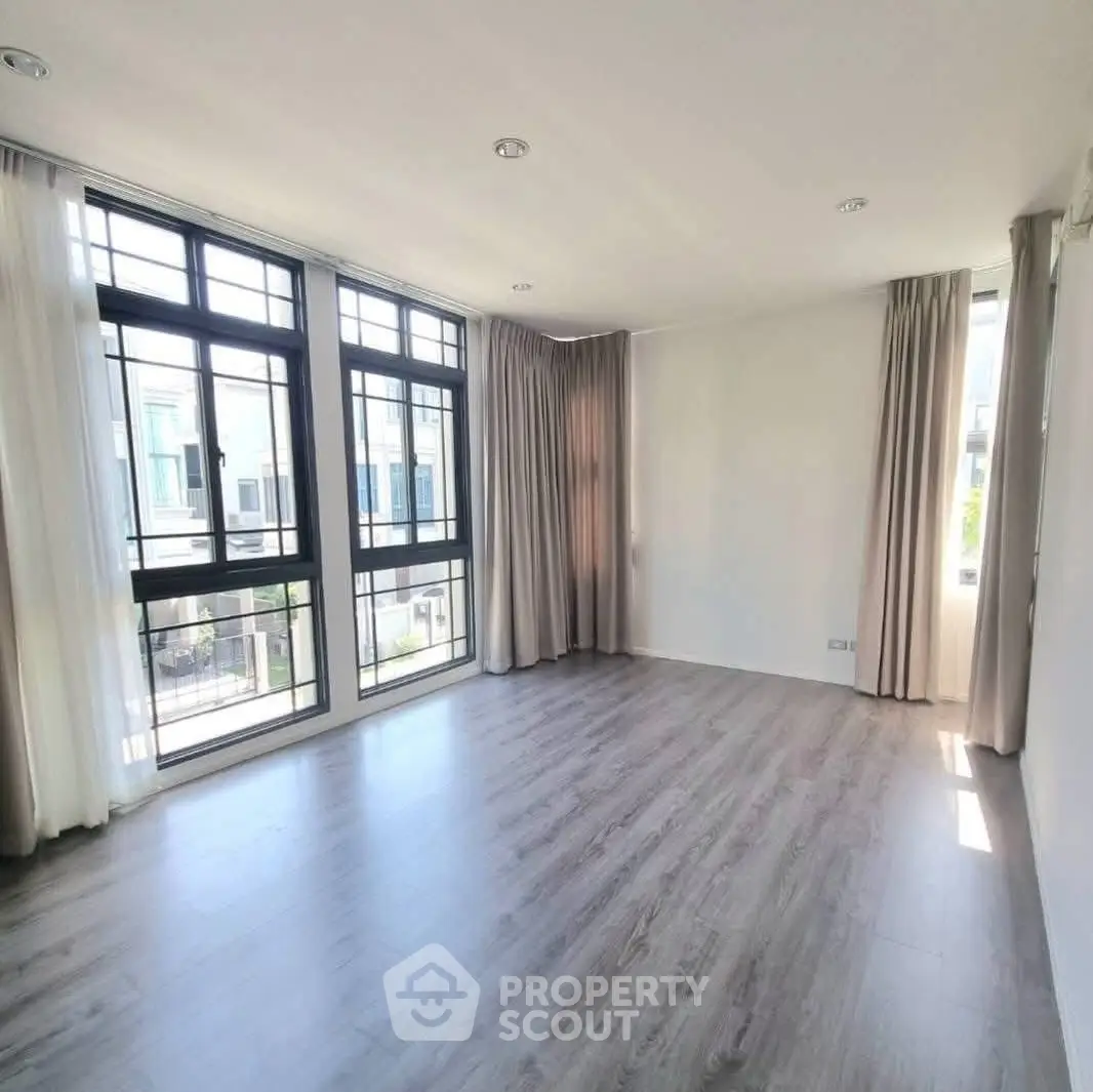 Spacious sunlit room with large windows and elegant flooring, perfect for modern living.