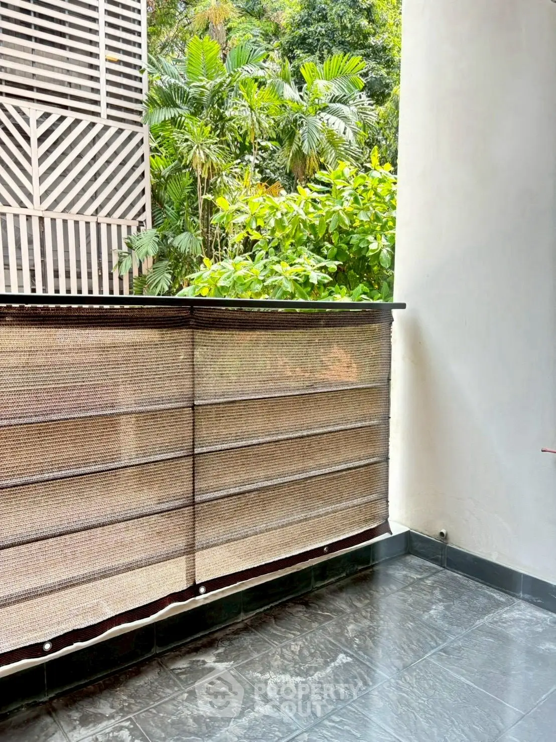 Charming balcony with lush greenery view and stylish privacy screen, perfect for relaxation.