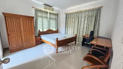Spacious bedroom with wooden furniture and large windows for natural light.