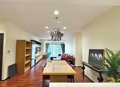 Spacious living room with elegant chandelier and city view, featuring modern furniture and hardwood floors.