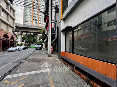 Urban street view with modern buildings and parked cars, showcasing city living environment.