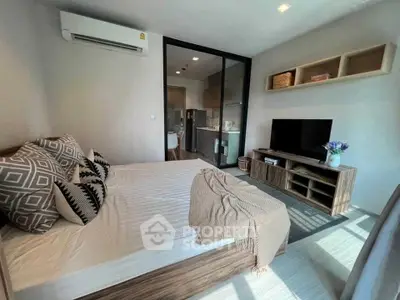 Modern bedroom with stylish decor and open kitchen layout, featuring cozy bedding and sleek furniture.