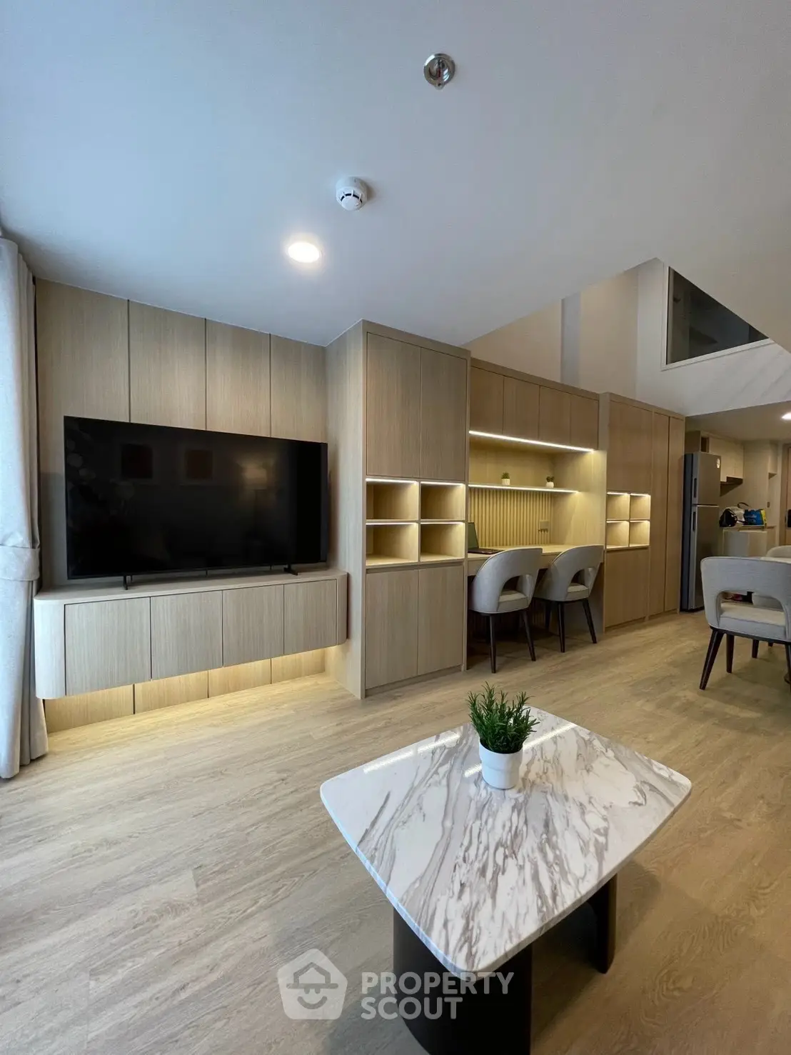 Modern living room with sleek wooden cabinetry and marble coffee table, perfect for stylish urban living.