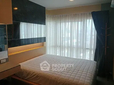 Cozy bedroom with large windows and modern decor in a high-rise apartment.