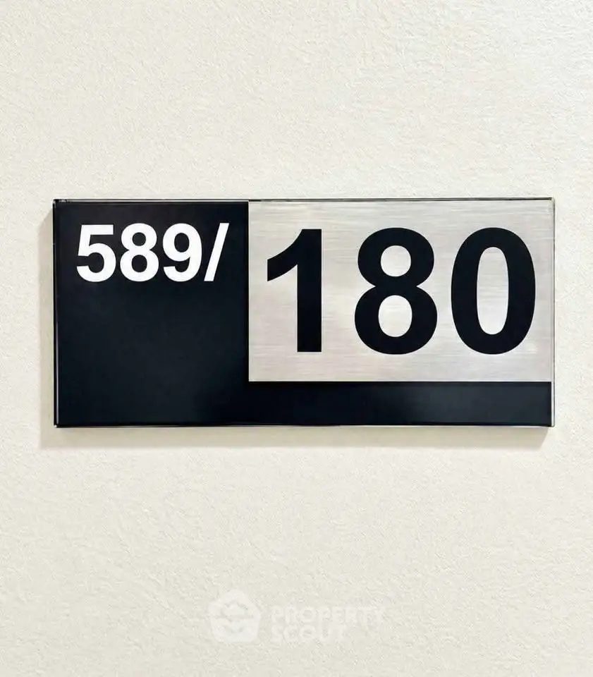 Modern apartment number sign with sleek black and silver design.
