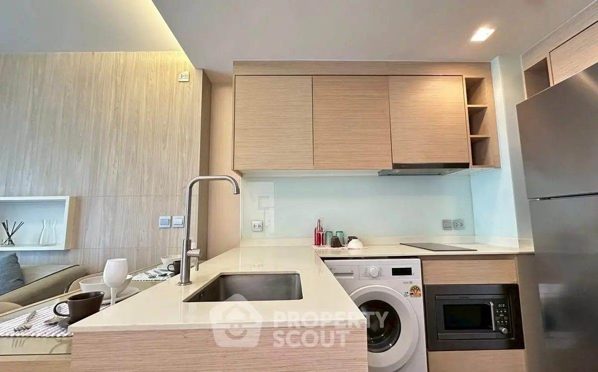 Modern kitchen with sleek cabinetry, integrated appliances, and cozy dining area in open-plan layout.