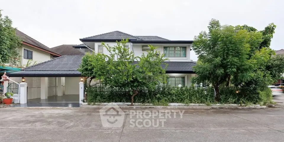 Charming two-story house with lush greenery and spacious driveway
