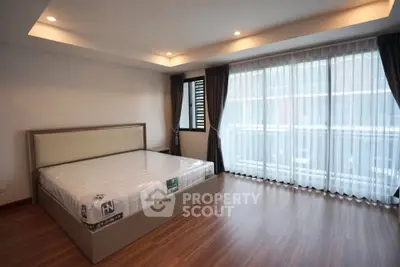 Spacious bedroom with large windows and modern design in a luxury apartment.