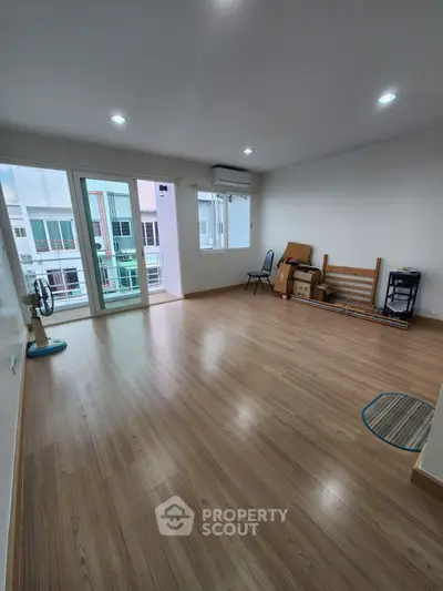 Spacious empty room with wooden flooring and large windows in modern apartment