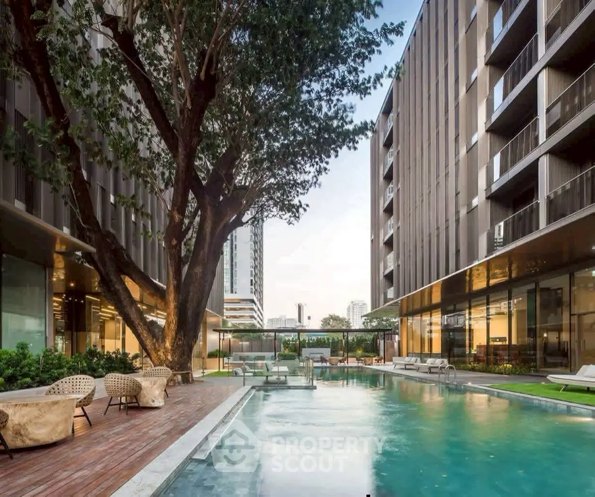 Luxurious modern apartment complex with a stunning outdoor pool and lush greenery.