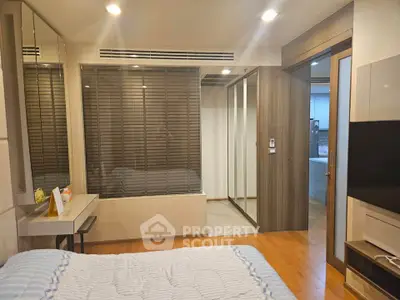 Modern bedroom with wooden flooring and mirrored closet doors in a stylish apartment.