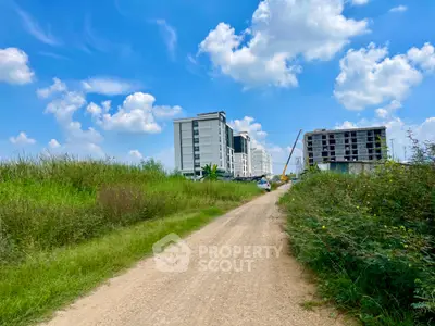 Emerging residential area with modern apartment buildings under a clear blue sky, surrounded by lush greenery, offering a blend of urban living and nature's tranquility.