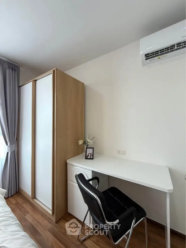 Modern study area with sleek desk and chair in a bright room, featuring a wardrobe and air conditioning.