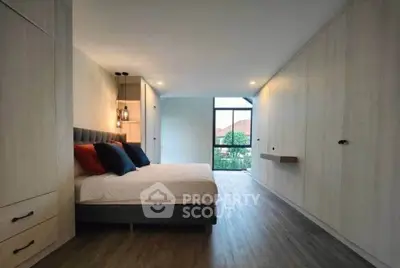 Spacious modern bedroom with large window and built-in wardrobes