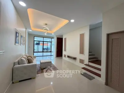 Modern living room with stylish ceiling lights and cozy sofa, featuring a staircase and large window view.