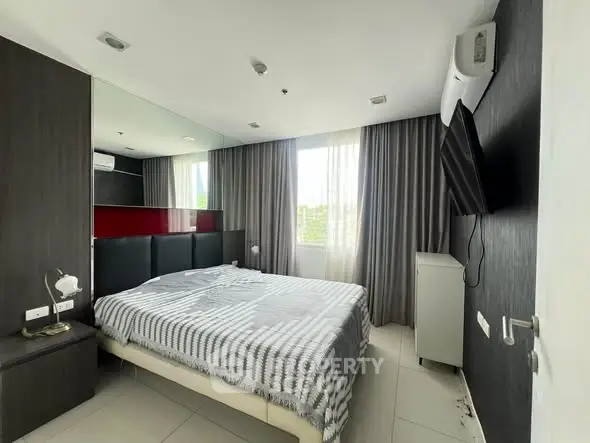 Modern bedroom with stylish decor, large window, and wall-mounted TV in a contemporary apartment.