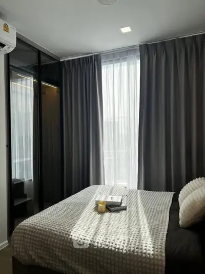 Cozy bedroom with modern decor and ample natural light through large windows.