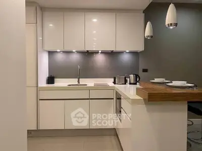 Modern kitchen with sleek white cabinets and breakfast bar in a stylish apartment.