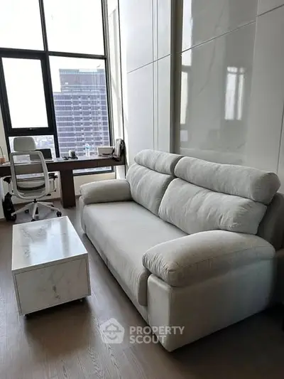 Modern living room with sleek sofa and stylish desk by large window