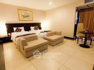 Spacious hotel room with twin beds and cozy seating area, perfect for relaxation.