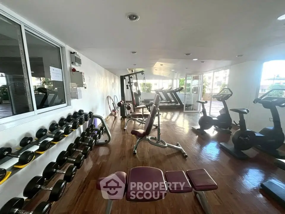 Spacious gym with modern equipment and wooden flooring in a residential building.