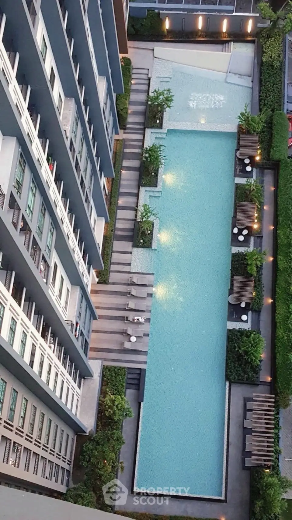 Stunning aerial view of modern apartment building with luxurious swimming pool and lush greenery.