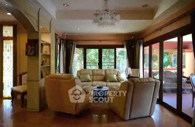 Spacious living room with elegant decor and large windows overlooking lush greenery.