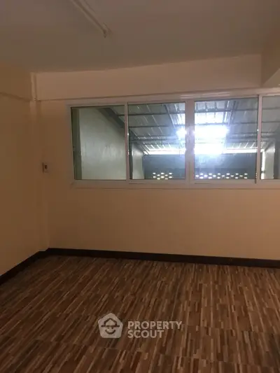 Spacious room with parquet flooring and large windows allowing ample natural light, ideal for a versatile living space.