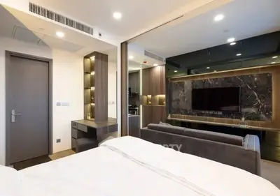 Modern bedroom with sleek design and integrated living area, featuring a large TV and stylish decor.