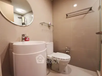 Modern bathroom with sleek fixtures and round mirror, featuring a contemporary design.