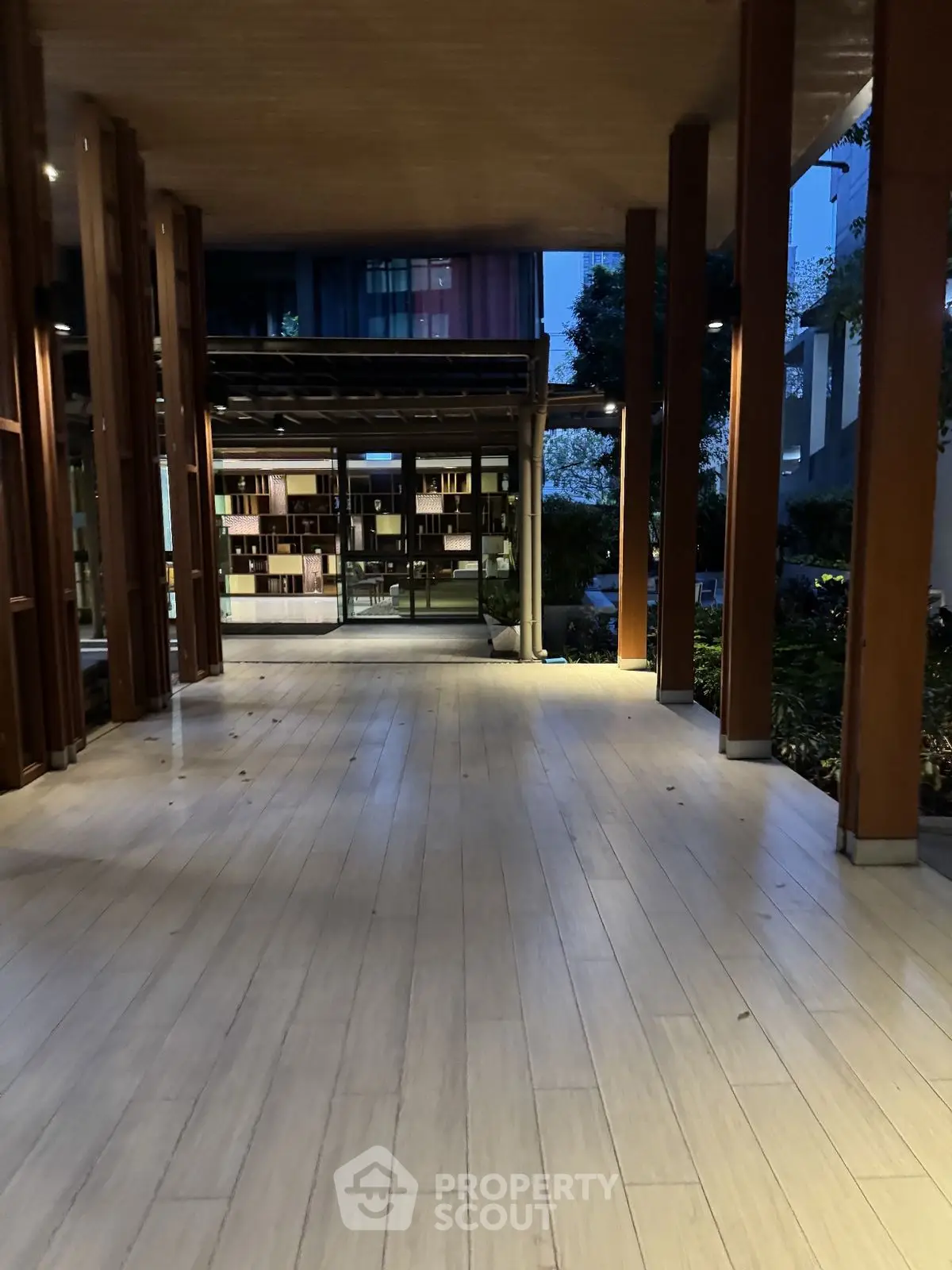 Modern building entrance with wooden flooring and glass walls at dusk