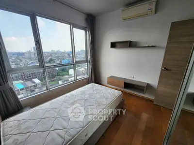 Bright bedroom with city view, wooden flooring, and air conditioning in modern apartment.