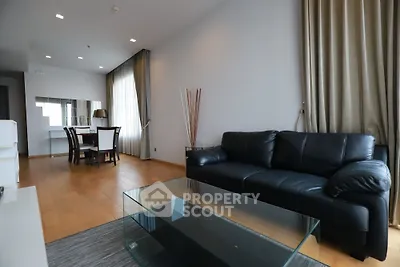 Spacious modern living room with sleek black leather sofa and elegant dining area.