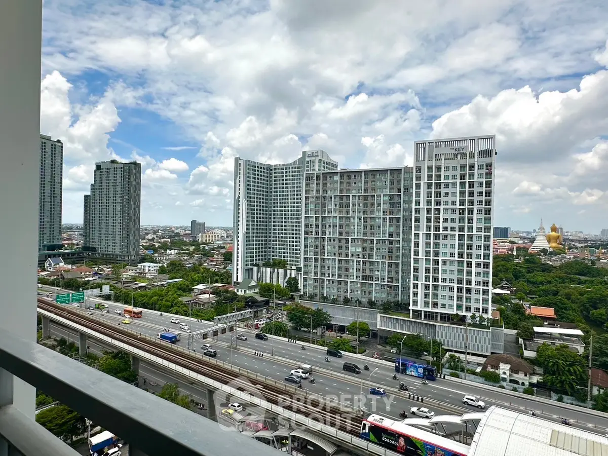 Stunning cityscape view from a high-rise balcony overlooking modern buildings and bustling highway.