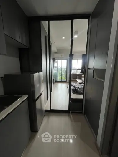 Modern apartment interior with sleek kitchen and open living area leading to a balcony with a view.