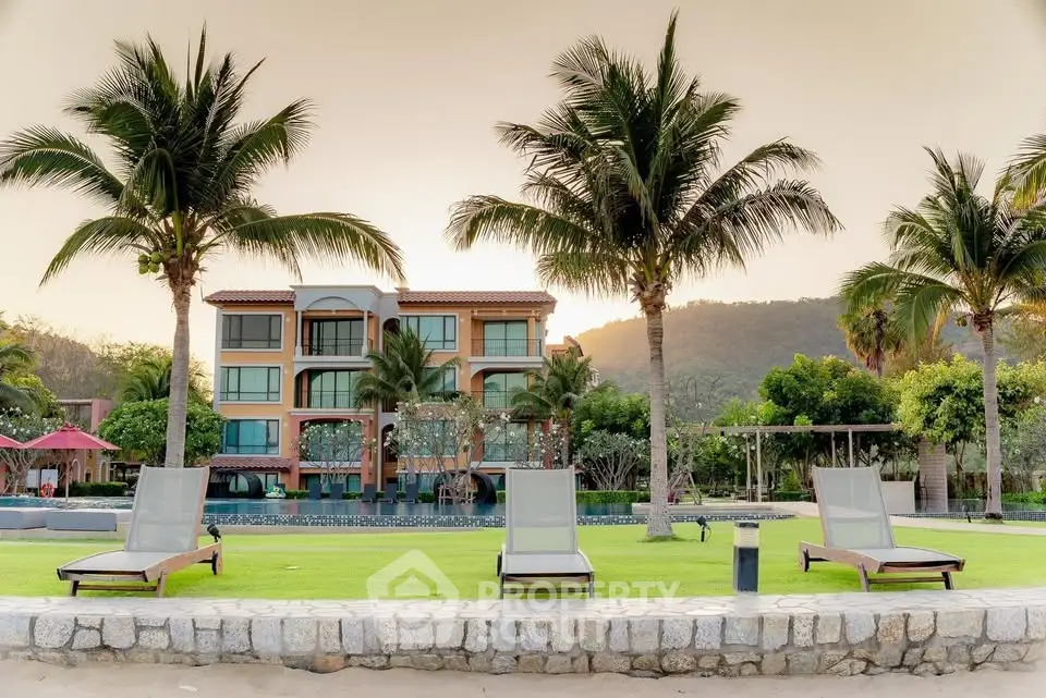 Luxurious beachfront property with palm trees and sun loungers, perfect for a tropical getaway.