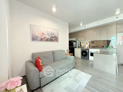 Modern living room with open kitchen, featuring sleek appliances and stylish decor.