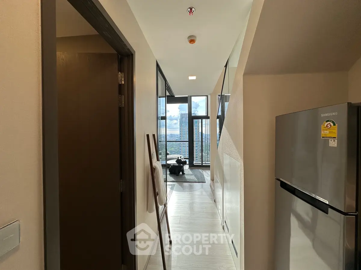 Modern apartment hallway leading to a bright living area with stunning city views.