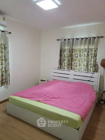 Cozy bedroom with modern decor and floral curtains, featuring a comfortable bed and warm lighting.