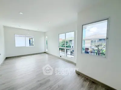 Spacious and bright living room with large windows and modern flooring, perfect for natural light lovers.