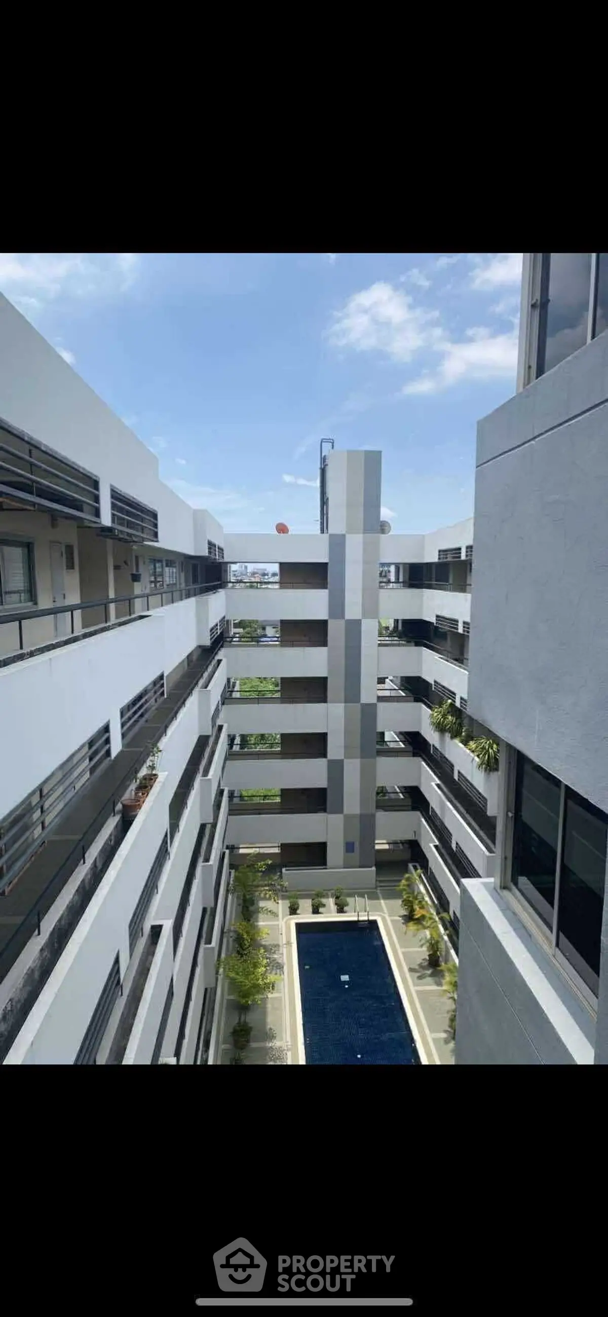Modern apartment building with central pool and sky view, showcasing contemporary architecture.