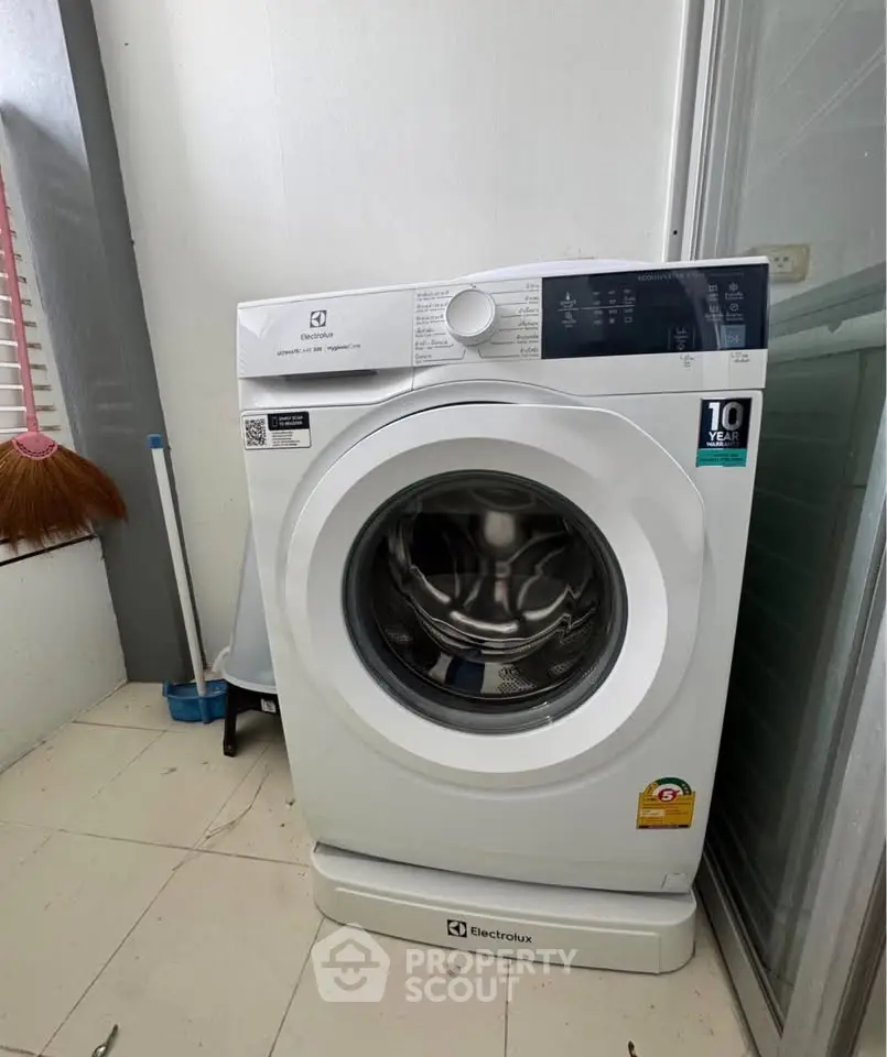 Modern Electrolux washing machine in a bright laundry area with tiled flooring.