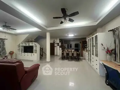 Spacious open-layout living room with modern furnishings and ceiling fans, perfect for family gatherings.